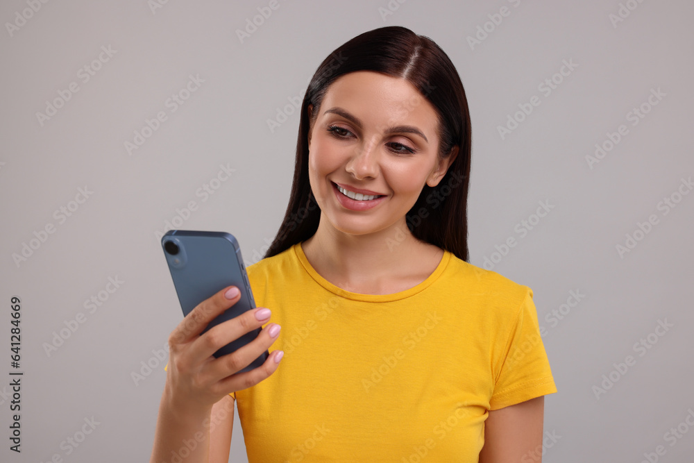 Young woman using smartphone on grey background Young woman using smartphone on grey background