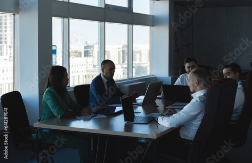 A team of young businessmen working and communicating together in an office. Corporate businessteam and manager in a meeting.