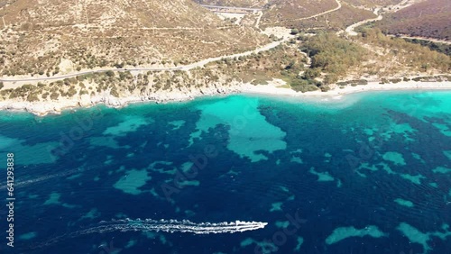 4k panoramic drone view of a small boat that sails from the crystal clear sea near the beach on the island of Sardinia in Italy