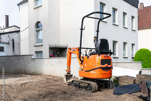 Fotografia Small orange crawler excavator at a construction site near a residential building
