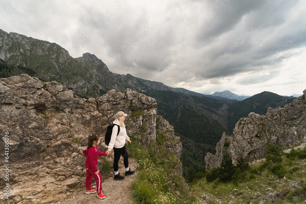 Mom with her little daughter on a hike in the Tatra Mountains, the sky is covered with storm clouds.