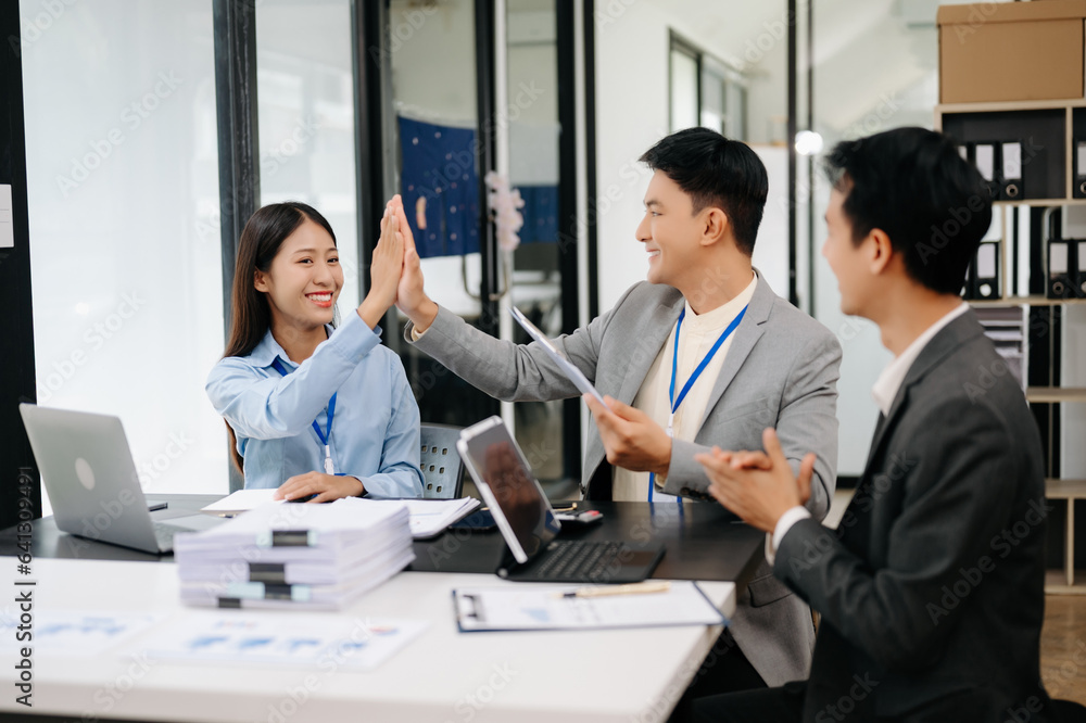 Group of Young Asian business team creative businesspeople coworker, teamwork celebrating achievement and in planning design in creative in office.. Group of Young Asian business team creative businesspeople coworker, teamwork celebrating achievement and in planning design in creative in office..