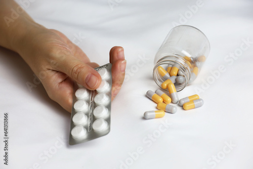 Pills in a palm of female hand on the bed. Concept of medication, vitamins or sleeping pill