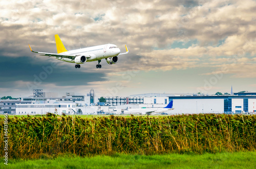 Airplane with landing gear in the sky with clouds. Flying passenger plane is landing at airport runway Bremen Airport. Side view photo