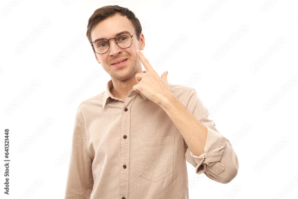 Portrait of young male points finger at eyeglasses on face isolated on white studio background. Vision check and loss of sight concept, eyewear shop Portrait of young male points finger at eyeglasses on face isolated on white studio background. Vision check and loss of sight concept, eyewear shop