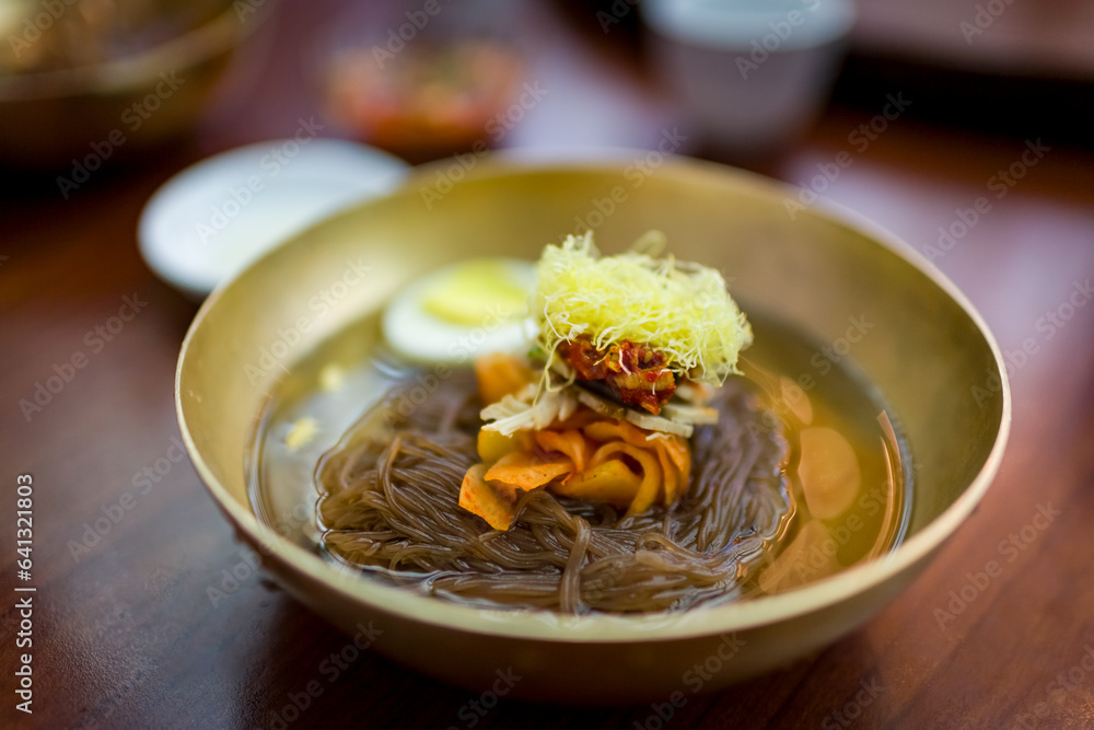 Delicious bowl of fresh Mul Naengmyeon, also called Pyongyang noodles: dish of North Korean origin which consists of long and thin handmade noodles, served with a spicy dressing Delicious bowl of fresh Mul Naengmyeon, also called Pyongyang noodles: dish of North Korean origin which consists of long and thin handmade noodles, served with a spicy dressing