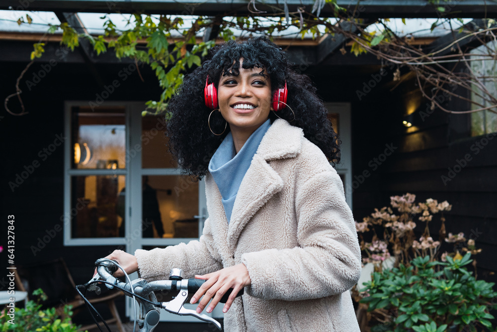 Smiling hispanic woman listening to music with headphones riding a ...