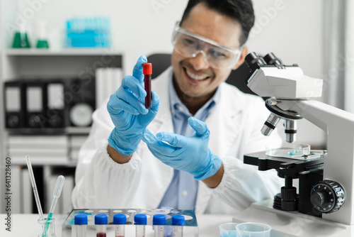 Doctor taking a blood sample tube from a rack with machines of analysis in the lab background, Technician holding blood tube test in the research laboratory.