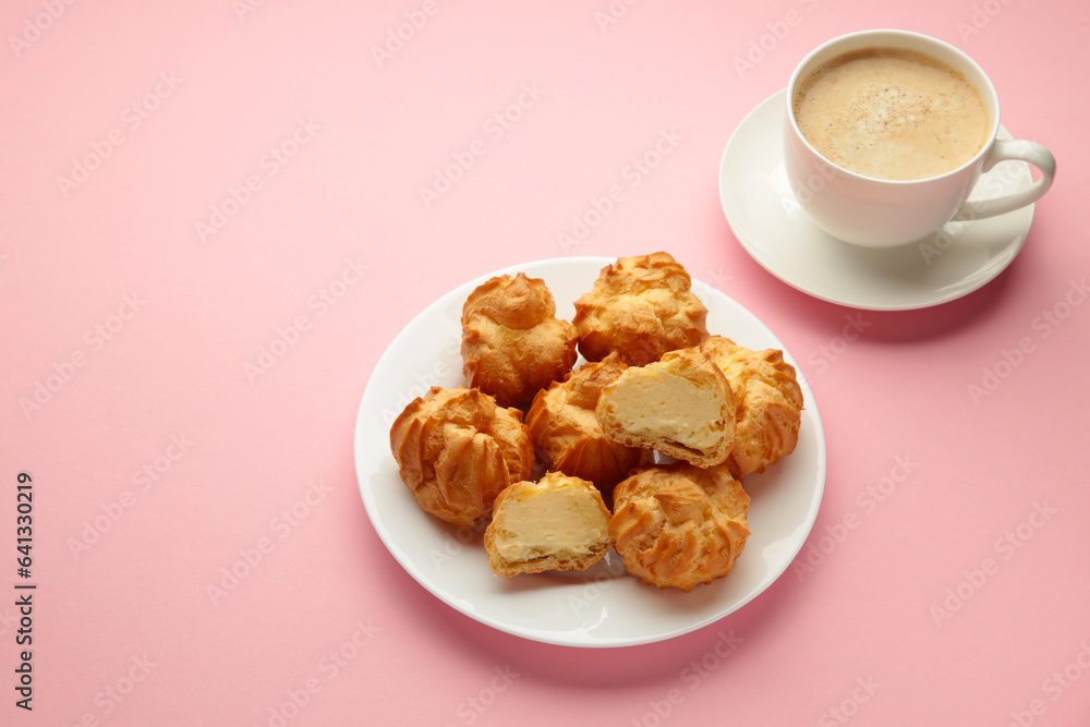 Homemade profiteroles with cream on plate with cup of coffee on pink background. Fresh baked golden profiterole. Homemade profiteroles with cream on plate with cup of coffee on pink background. Fresh baked golden profiterole.