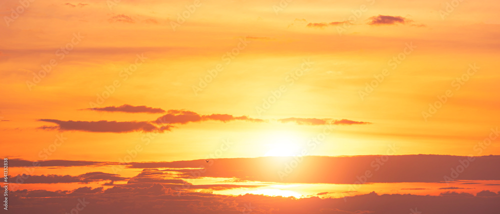 Panoramic colorful evening sky background, yellow sunlight breaking through the dramatic clouds on sunset sky in golden hour time 