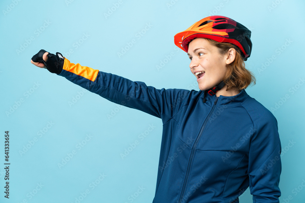 Young cyclist woman isolated on blue background giving a thumbs up gesture Young cyclist woman isolated on blue background giving a thumbs up gesture