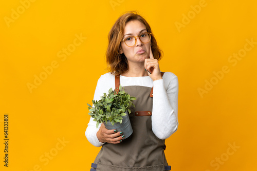 Young Georgian woman holding a plant isolated on yellow background thinking an idea