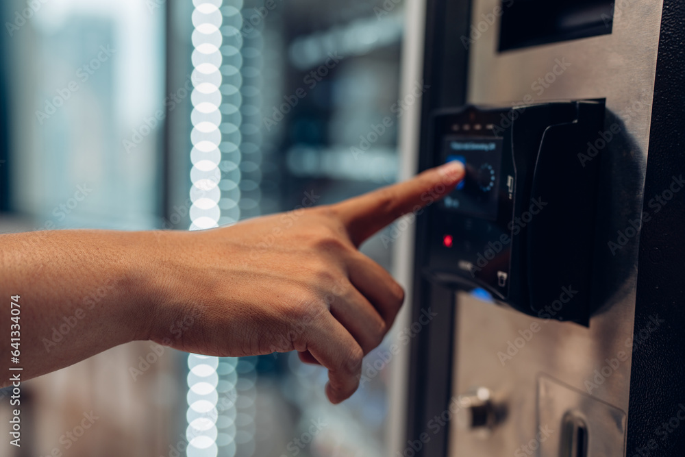 Naklejka premium Close up view of woman's finger pushing number button on keyboard of snack vending machine. Self-used technology and consumption concept
