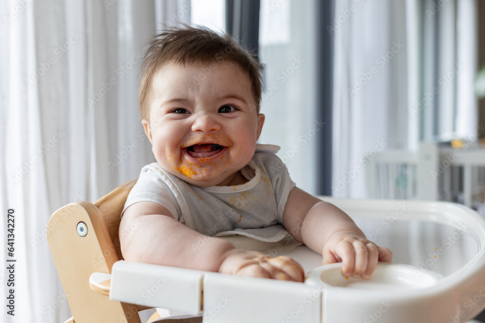 Funny baby with pumpkin food on face smiling after feeding Funny baby with pumpkin food on face smiling after feeding