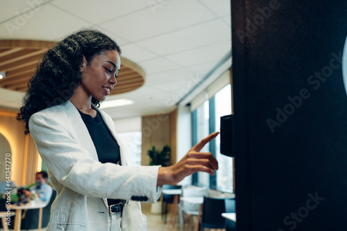 Close up view of woman's finger pushing number button on keyboard of snack vending machine. Self-used technology and consumption concept	 photo