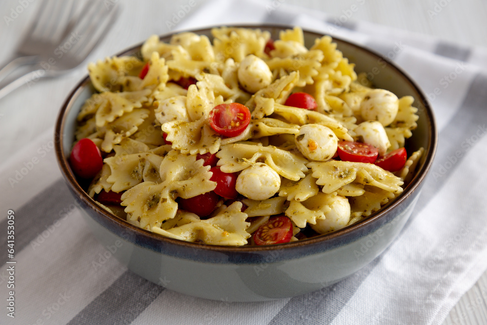 Homemade Pesto Pasta with Tomatoes ans Mozzarella in a Bowl, low angle view. Homemade Pesto Pasta with Tomatoes ans Mozzarella in a Bowl, low angle view.