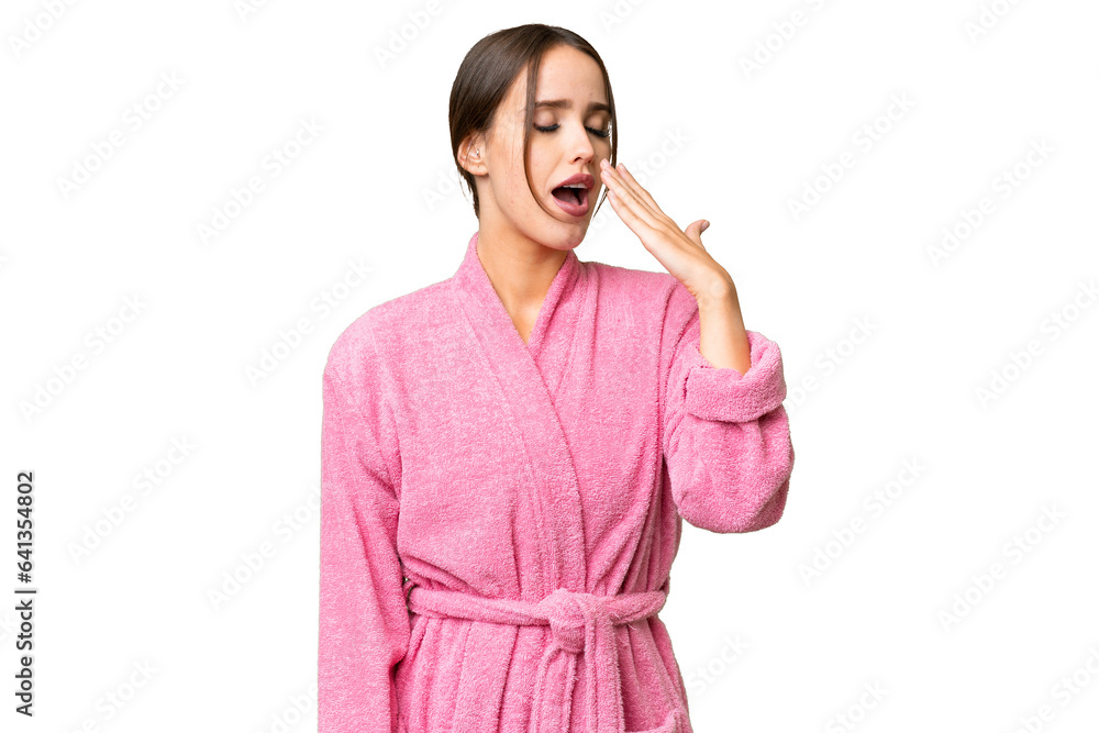 Young beautiful woman in a bathrobe over isolated chroma key background yawning and covering wide open mouth with hand Young beautiful woman in a bathrobe over isolated chroma key background yawning and covering wide open mouth with hand