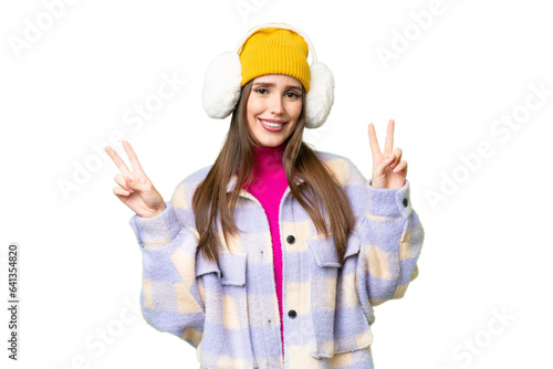 Young woman wearing winter muffs over isolated chroma key background showing victory sign with both hands