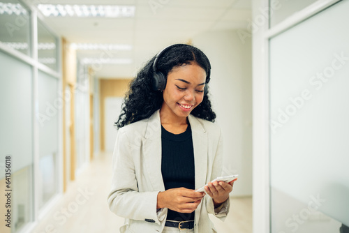 Shot of elegant young business woman smiling and using mobile phone while walking, Copy space.