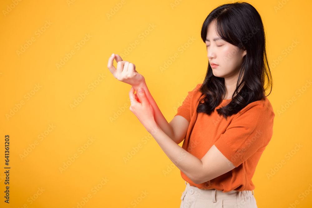 Woman wrist pain due to arthritis showcased in yellow studio portrait. Concept of injury and physical discomfort. Woman wrist pain due to arthritis showcased in yellow studio portrait. Concept of injury and physical discomfort.