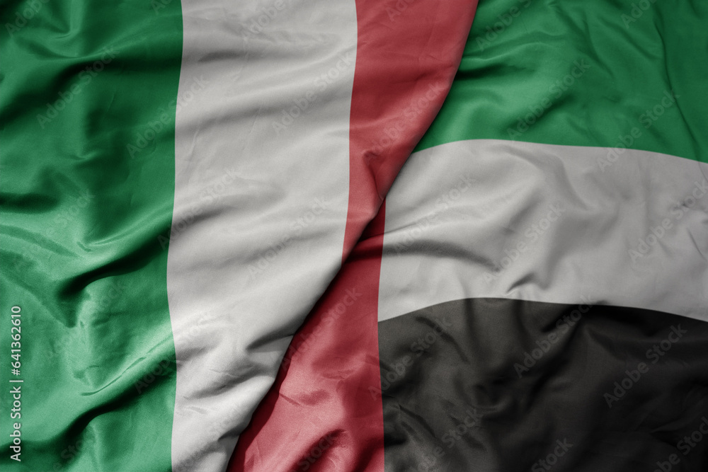 big waving national colorful flag of italy and national flag of united arab emirates .