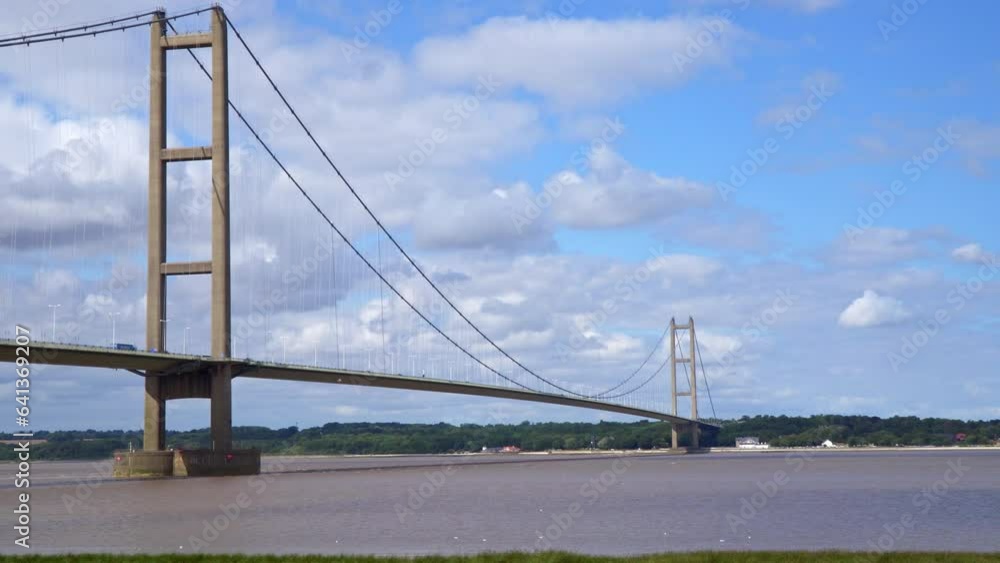 Aerial drone view of Humber Bridge, 12th largest suspension span, gracefully crossing River Humber, connecting Lincolnshire to Humberside with traffic. Aerial drone view of Humber Bridge, 12th largest suspension span, gracefully crossing River Humber, connecting Lincolnshire to Humberside with traffic.
