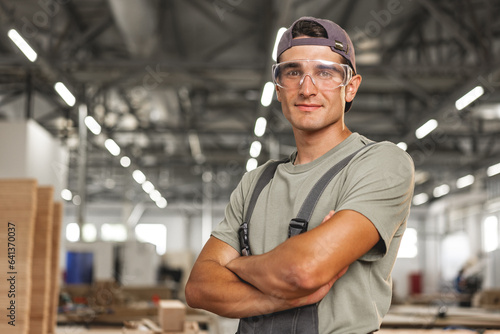 Portrait of young male carpenter standing in the wood workshop