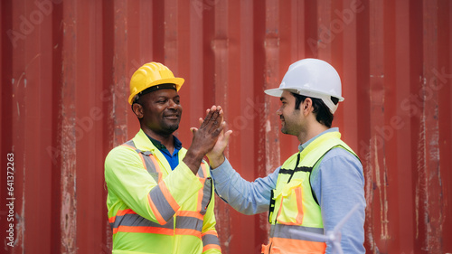 Team worker stack hand and shake hands to show success work at Container cargo harbor. Logistics concept inside the shipping, import, and export industries.