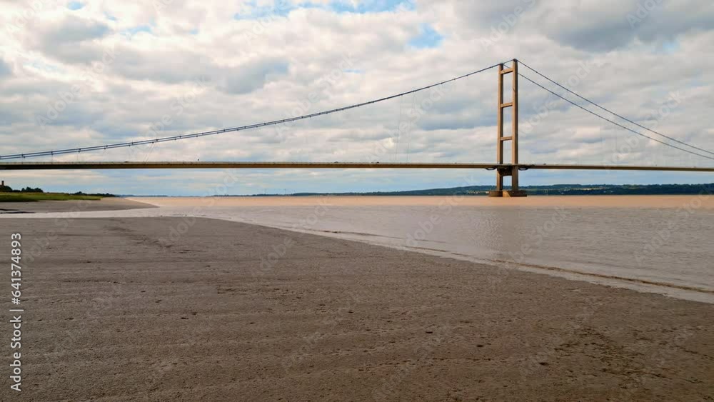Aerial drone view of Humber Bridge, 12th largest suspension span, gracefully crossing River Humber, connecting Lincolnshire to Humberside with traffic. Aerial drone view of Humber Bridge, 12th largest suspension span, gracefully crossing River Humber, connecting Lincolnshire to Humberside with traffic.