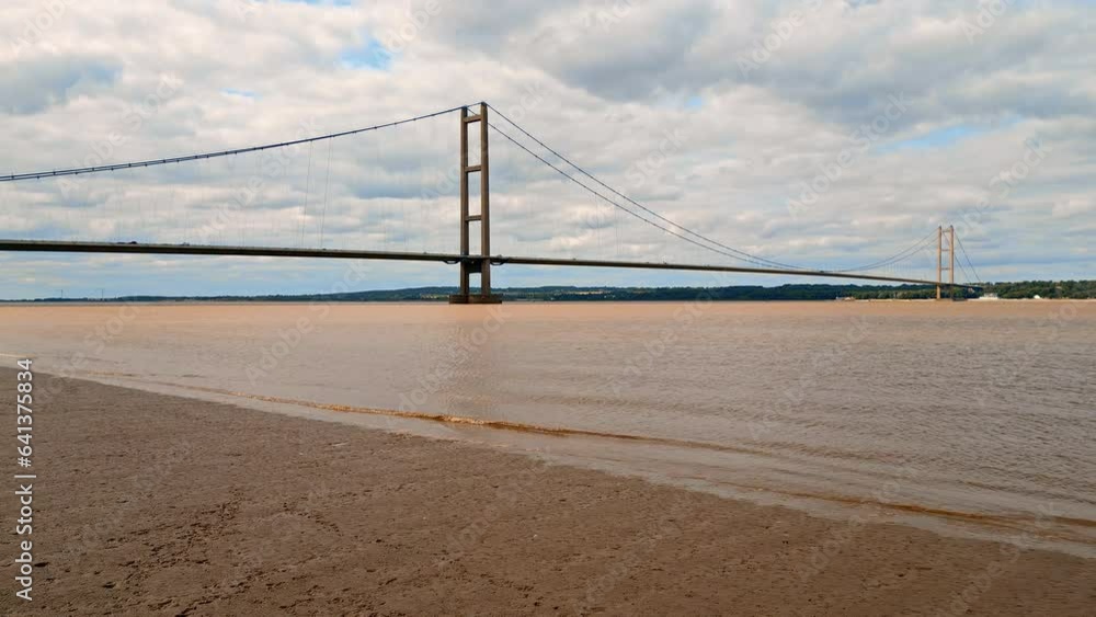 Aerial drone view of Humber Bridge, 12th largest suspension span, gracefully crossing River Humber, connecting Lincolnshire to Humberside with traffic. Aerial drone view of Humber Bridge, 12th largest suspension span, gracefully crossing River Humber, connecting Lincolnshire to Humberside with traffic.
