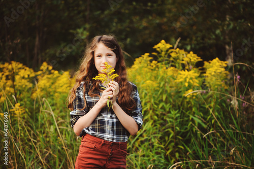 preteen 11 years old kid girl walking on summer countryside road, enjoying vacations outdoor