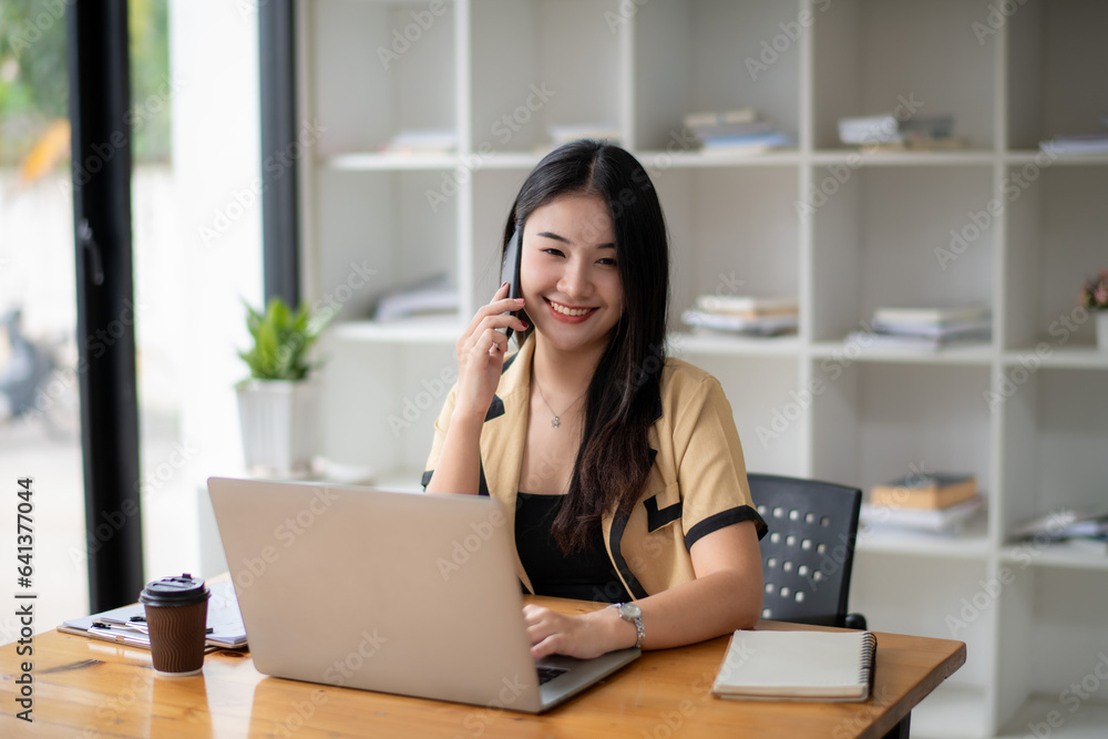 Businesswoman using laptop to work and communicate with colleagues or clients via mobile phone. Businesswoman using laptop to work and communicate with colleagues or clients via mobile phone.