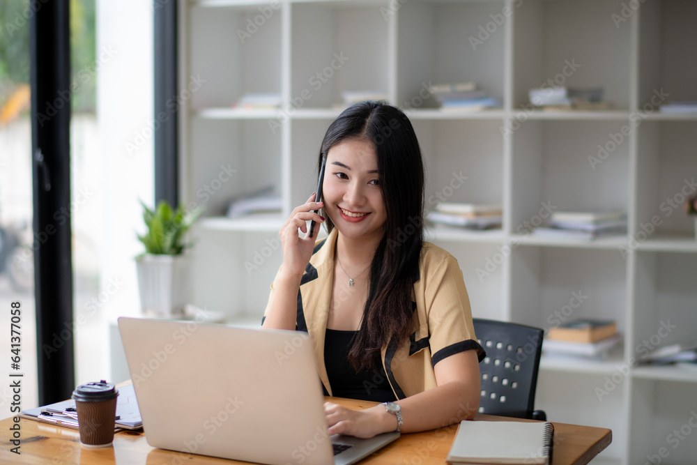 Businesswoman using laptop to work and communicate with colleagues or clients via mobile phone. Businesswoman using laptop to work and communicate with colleagues or clients via mobile phone.