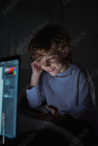 Content boy doing homework in darkness