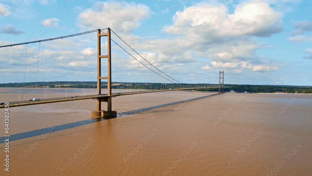Aerial drone view of Humber Bridge, 12th largest suspension span, gracefully crossing River Humber, connecting Lincolnshire to Humberside with traffic. Aerial drone view of Humber Bridge, 12th largest suspension span, gracefully crossing River Humber, connecting Lincolnshire to Humberside with traffic.