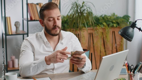 Rich middle eastern businessman working on laptop pc counting money cash, calculate earnings income profit at home office workplace. Professional freelancer man. Business people. Employment occupation photo