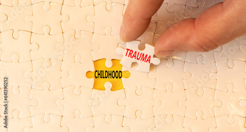 Childhood trauma symbol. Concept words Childhood trauma on beautiful white puzzles. Beautiful yellow paper background. Psychologist hand. Business psychology childhood trauma concept. Copy space.