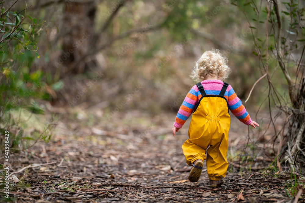 baby walking in a park in yellow overalls