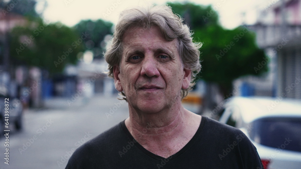 Close-up face of a senior man staring at camera with neutral stern expression standing in urban setting, portrait of person at old age Close-up face of a senior man staring at camera with neutral stern expression standing in urban setting, portrait of person at old age
