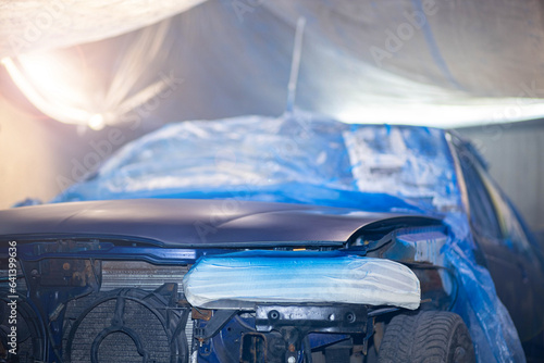 painting car body blue in car paint garage with colorful gun