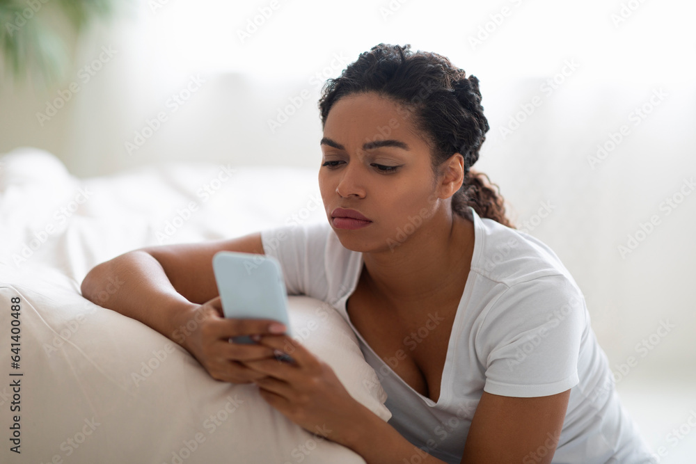 Upset Yong Black Woman Reading Message On Smartphone At Home Upset Yong Black Woman Reading Message On Smartphone At Home