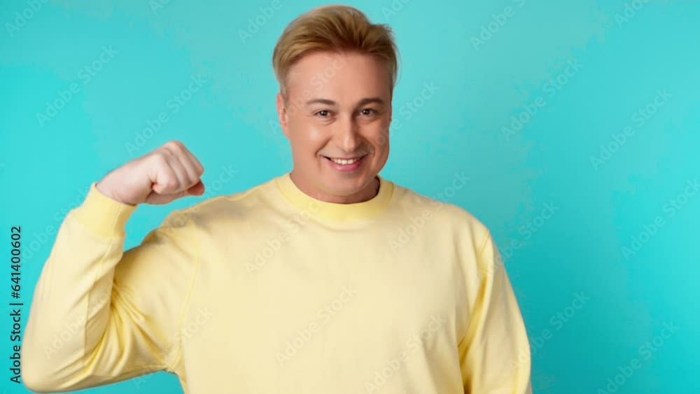 Arm, bicep, muscle and athletic man for fun, sport, health and fitness. Happy smiling guy showing bicep with confident expression, bodybuilding strength power. Studio shot isolated on blue background Arm, bicep, muscle and athletic man for fun, sport, health and fitness. Happy smiling guy showing bicep with confident expression, bodybuilding strength power. Studio shot isolated on blue background