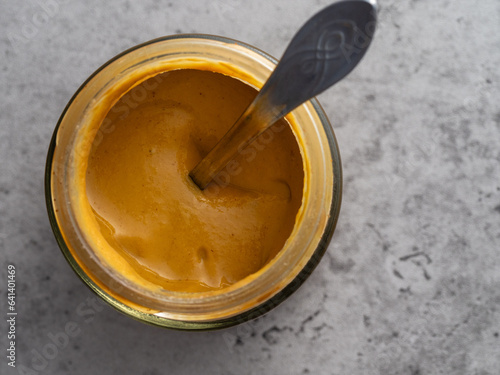 Jar of mustard with a silver spoon