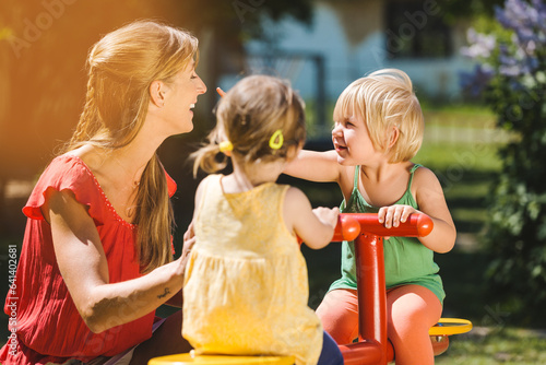 Children and nursery school teacher playing outdoors on a roundabout