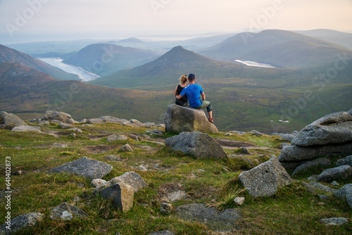 Couple sitting on the rock. Panoramic view of the Mourne Mountains, beautiful part of Northern Ireland