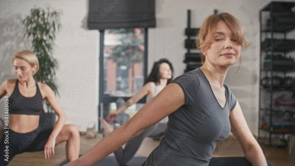 Team of sporty women streching their legs on fitness mats in cozy wellness center. Strengthening and healing their bodies. Healthy people training together in tranquility atmosphere. Team of sporty women streching their legs on fitness mats in cozy wellness center. Strengthening and healing their bodies. Healthy people training together in tranquility atmosphere.
