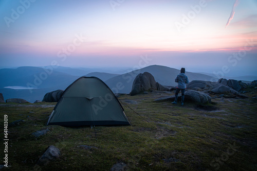 Girl watching sunset. Tent on the top of mountain.  Panoramic view of the Mourne Mountains  beautiful part of Northern Ireland