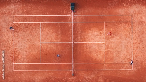 Zenith aerial view of red clay tennis courts with unrecognizable tennis players