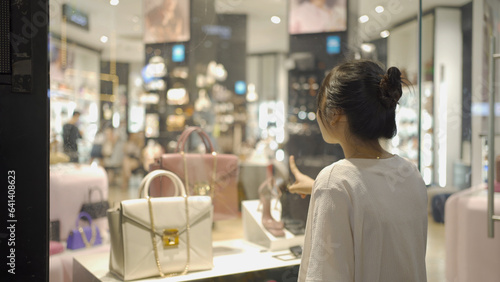 Portrait of happy Asian Vietnamese woman shopping a luxury bag at a mall in Hanoi city, Vietnam. Retail shops