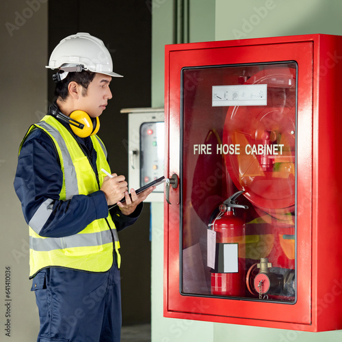 Photography Building inspector man using digital tablet checking fire hose cabinet